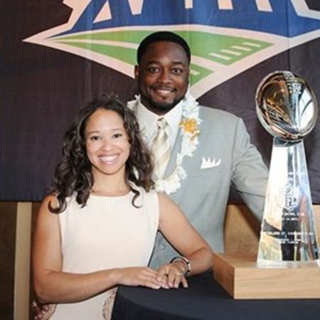 Mike and Kiya posing for a picture in front of trophy earned by Mike Tomlin.